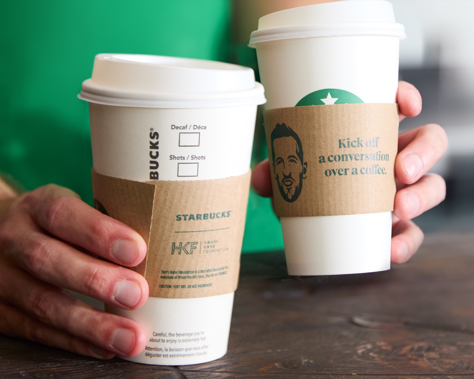 Two Starbucks cups held together over a coffeehouse counter